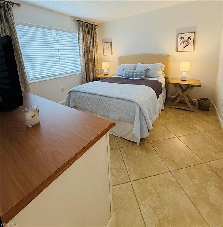 3250 10th Street North, Unit C8 Naples, FL 34103 - Photo 13 of 24 Bedroom featuring neutral-toned tile flooring, light cream wall paint, and a window with blinds