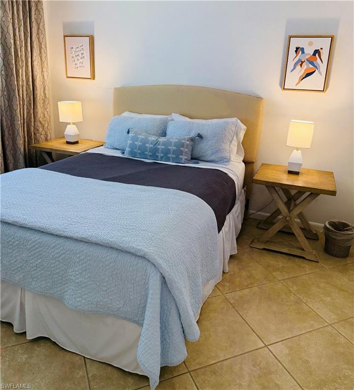 3250 10th Street North, Unit C8 Naples, FL 34103 - Photo 14 of 24 Bedroom featuring a neutral upholstered headboard and light-toned tile flooring