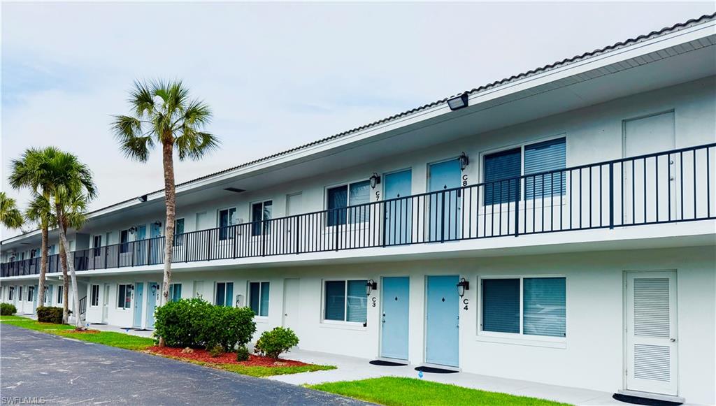 3250 10th Street North, Unit C8 Naples, FL 34103 - Photo 22 of 24 White exterior with light blue unit entry doors and black iron balcony railings