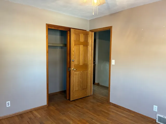 a view of an empty room with wooden floor and closet