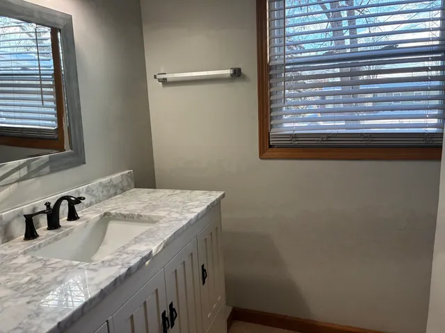 a bathroom with a granite countertop sink and a window