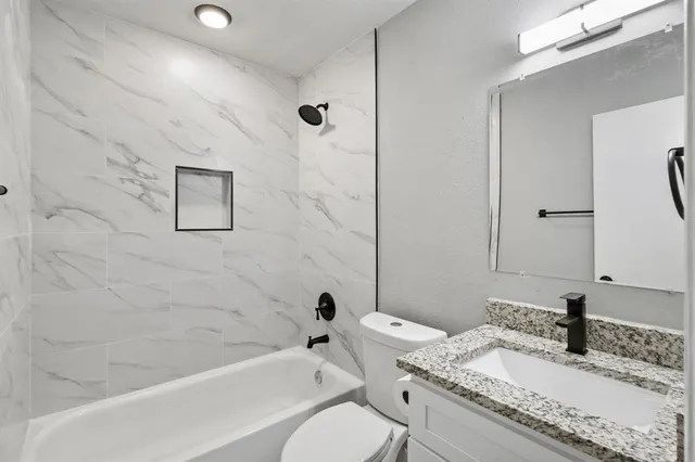 a bathroom with a granite countertop sink toilet and shower