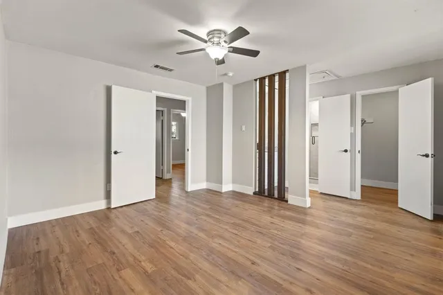 an empty room with wooden floor and a ceiling fan