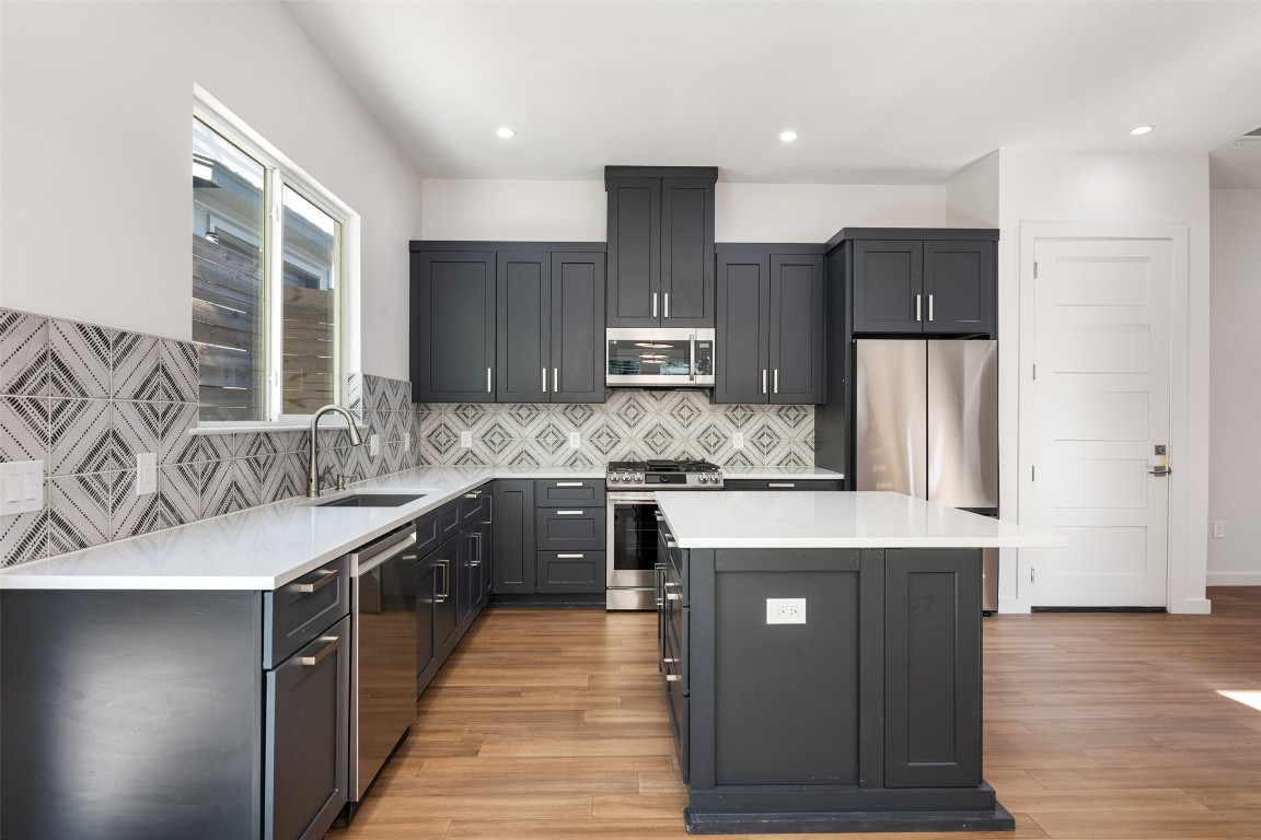 3010 Webberville Road, Unit 1 Austin, TX 78702 - Photo 13 of 40 a kitchen with stainless steel appliances granite countertop a refrigerator a sink dishwasher a stove and oven with wooden floor