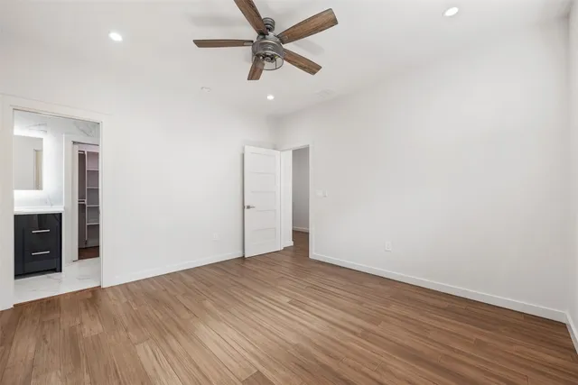 an empty room with wooden floor fan and windows