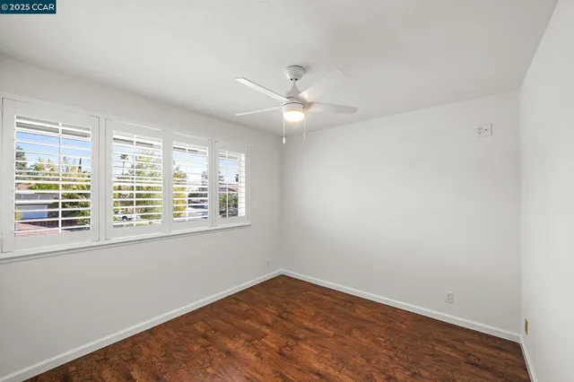 an empty room with a fan & a window