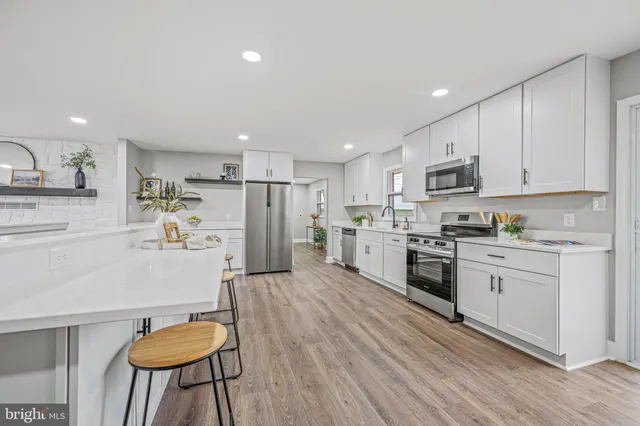 a kitchen with kitchen island wooden floors appliances and cabinets