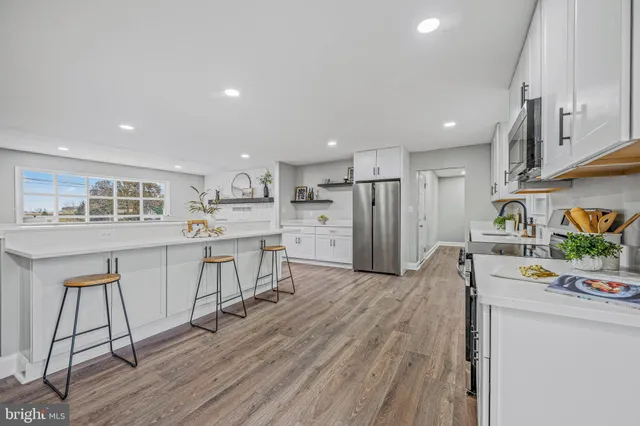 a kitchen with stainless steel appliances granite countertop a refrigerator sink and white cabinets