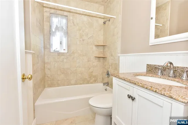 a bathroom with a granite countertop sink a toilet and bathtub