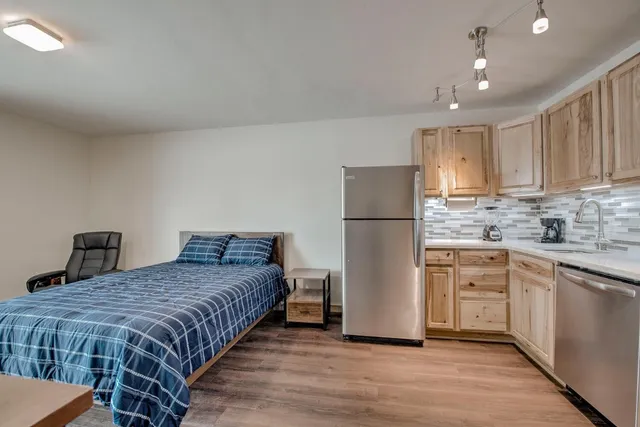 a spacious bedroom with a bed and a refrigerator