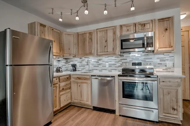 a kitchen with stainless steel appliances granite countertop a refrigerator a stove a sink and a microwave