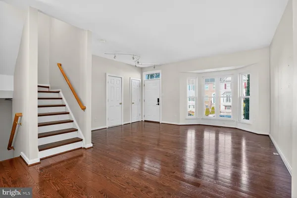 a view of an empty room with wooden floor and stairs