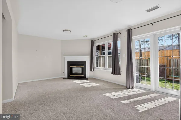 a view of an empty room with wooden floor and a kitchen