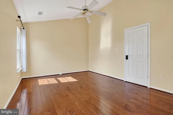 an empty room with wooden floor fan and windows