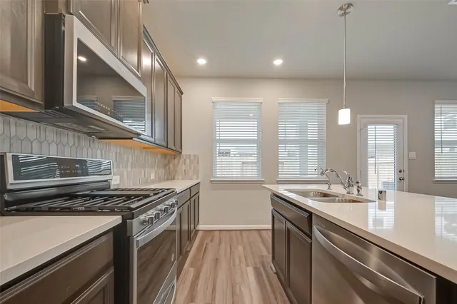 a kitchen with stainless steel appliances granite countertop a sink a oven and wooden floor