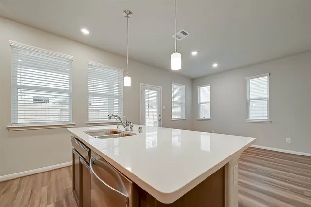 a kitchen with kitchen island granite countertop a sink a counter space appliances and cabinets