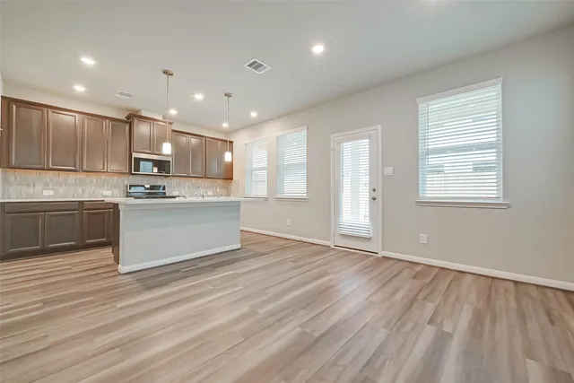 a view of kitchen with kitchen island stainless steel appliances cabinets and wooden floor