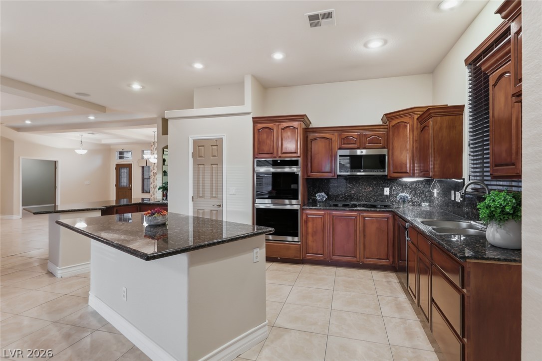 1104 Norellat Road Henderson, NV 89011 - Photo 15 of 52 Rich wood cabinetry paired with polished stone countertops defines this open-concept culinary space.