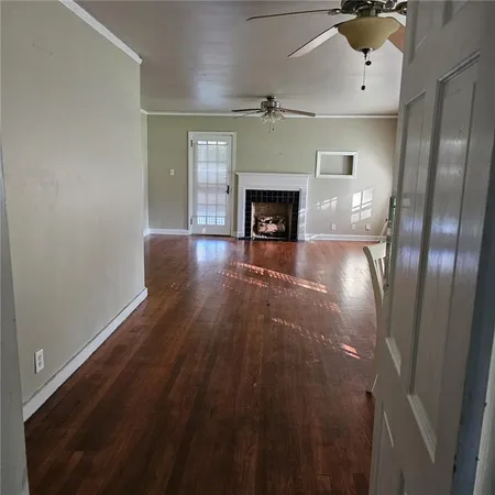 an empty room with wooden floor fireplace and windows