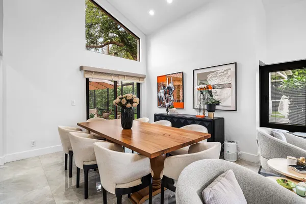 a kitchen with stainless steel appliances a refrigerator a stove a sink a dining table and chairs with wooden floor