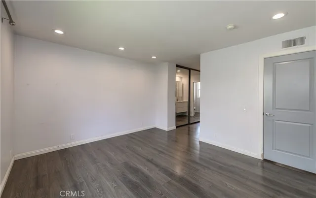 a view of an empty room with wooden floor and closet