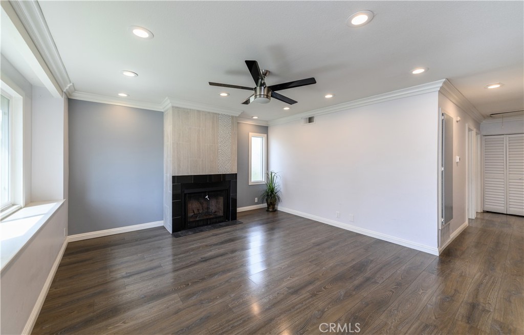 2 Hollowglen, Unit 7 Irvine, CA 92604 - Photo 5 of 31 an empty room with wooden floor a ceiling fan a fireplace and windows
