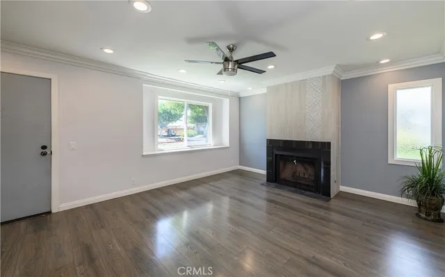 a view of an empty room with wooden floor fireplace and a window