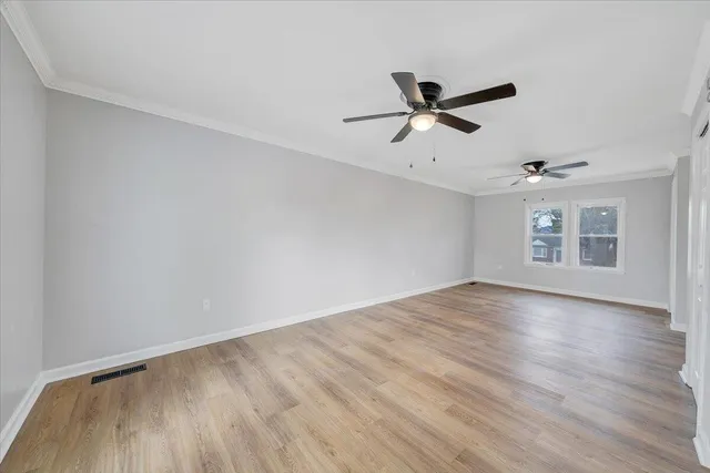 an empty room with wooden floor ceiling fan and windows