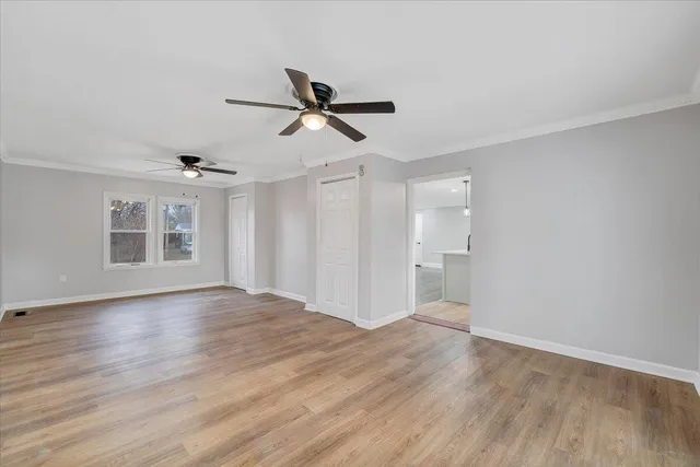 a view of empty room with wooden floor and ceiling fan