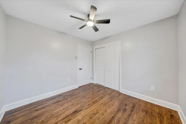 an empty room with wooden floor and ceiling fan