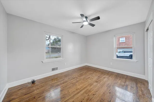 a view of a big room with wooden floor and windows