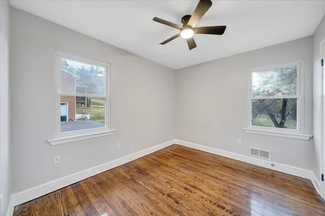 a view of empty room with wooden floor and fan