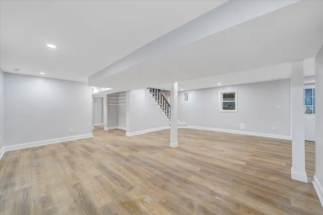 a view of an empty room with wooden floor and window