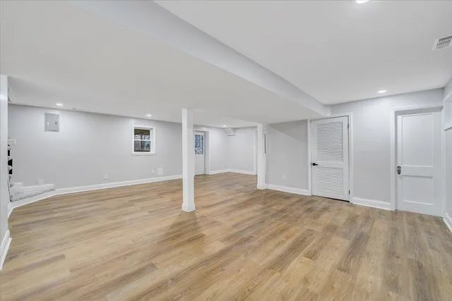 a view of an empty room with wooden floor and window