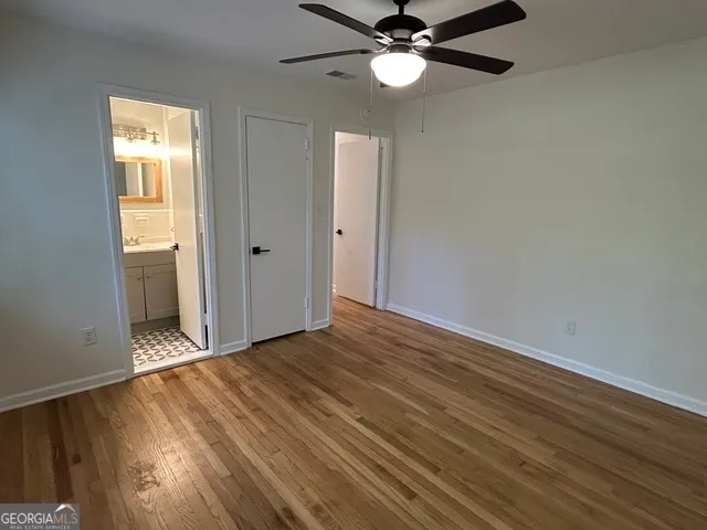 an empty room with wooden floor fan and windows