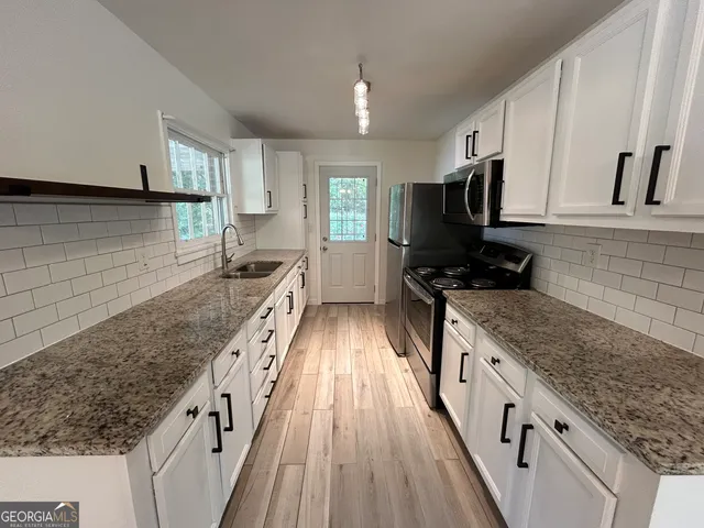 a kitchen with granite countertop a sink stove and cabinets