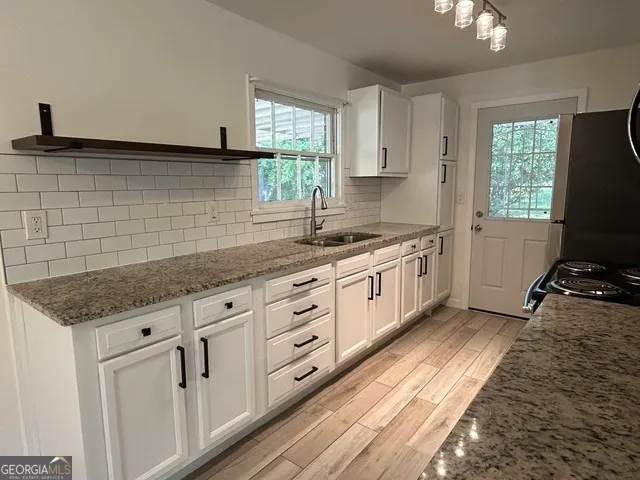 a kitchen with granite countertop white cabinets and a stove