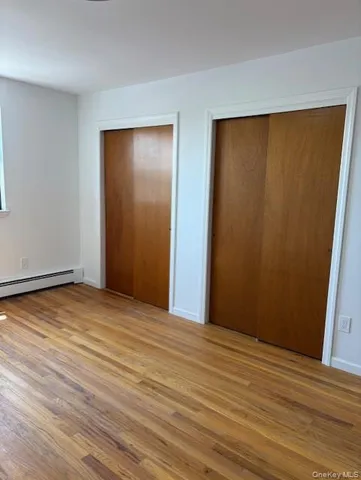 a view of an empty room with wooden floor and closet