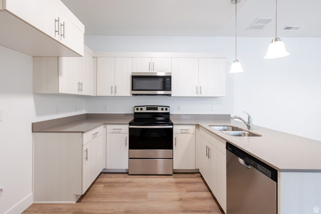 4664 South 680th West, Unit S304 Mapleton, UT 84664 - Photo 11 of 16 U-shaped kitchen featuring white cabinetry, gray countertops, stainless steel appliances, and wood-finish flooring