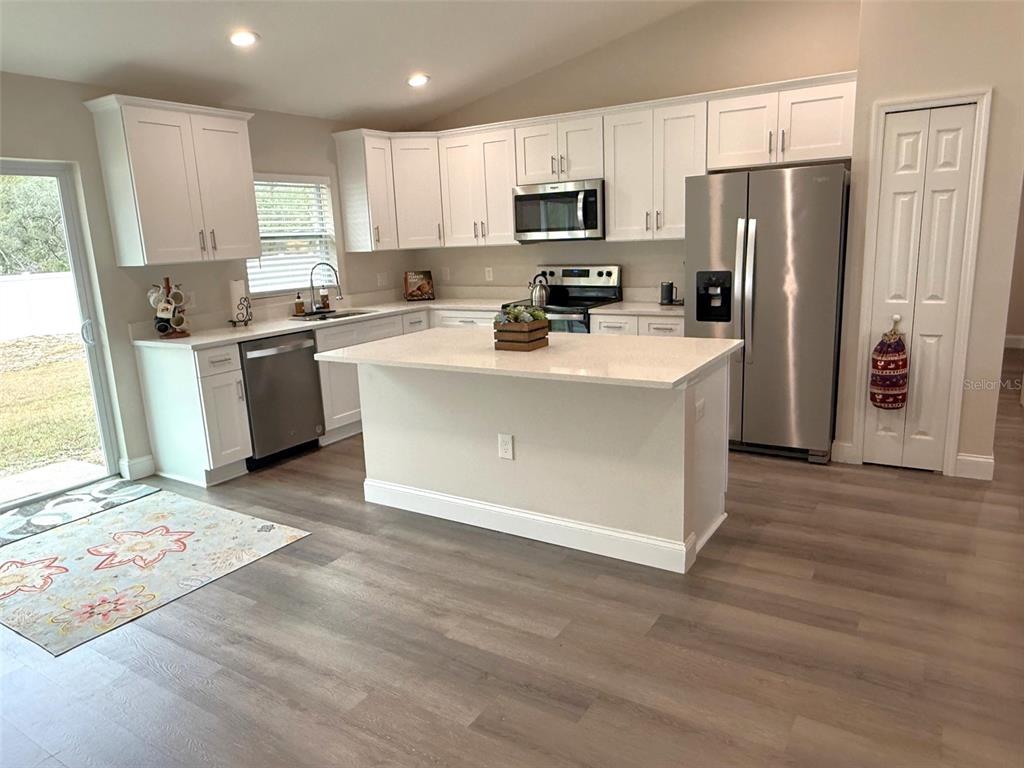 3791 Southwest 166th Pl Road Ocala, FL 34473 - Photo 7 of 43 a kitchen with kitchen island a refrigerator stove a sink and a oven with wooden floor