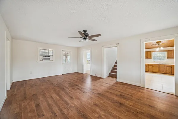 a view of empty room with wooden floor and ceiling fan