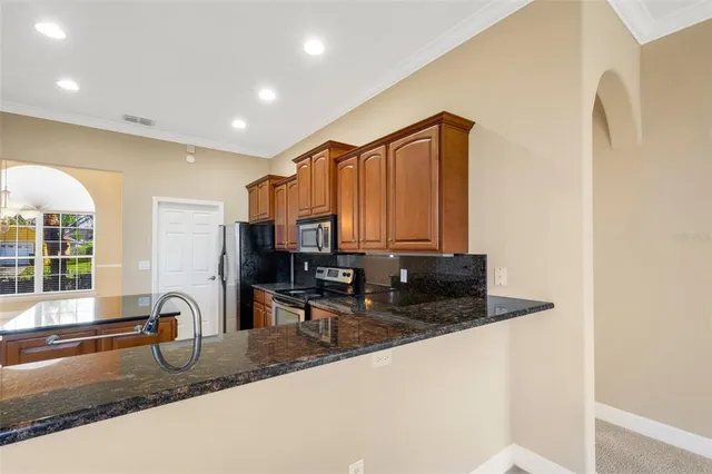 a kitchen with granite countertop a sink a stove and cabinets