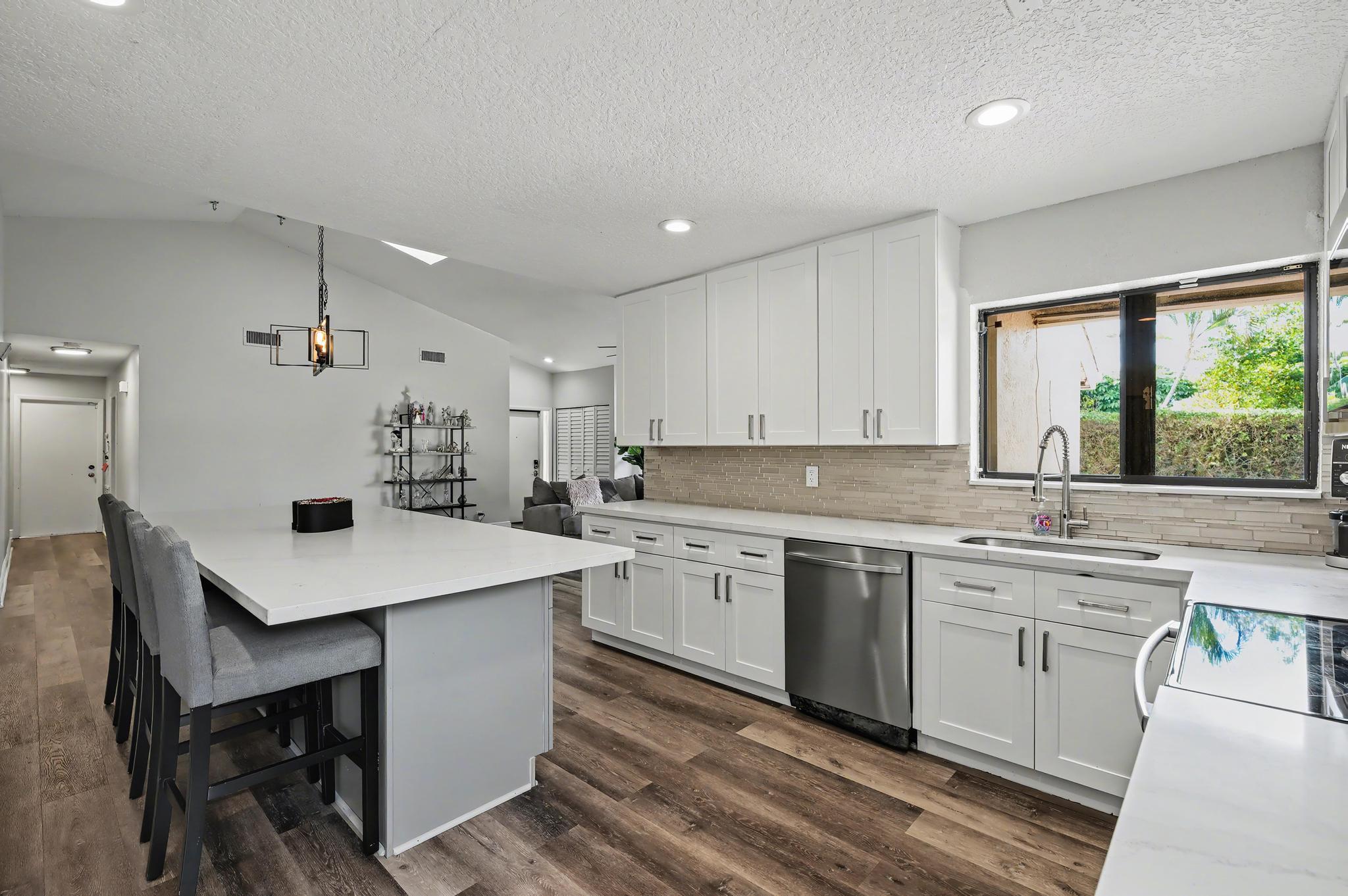 7855 Stanway Place Boca Raton, FL 33433 - Photo 4 of 24 a kitchen with a sink a stove a refrigerator and white cabinets with wooden floor
