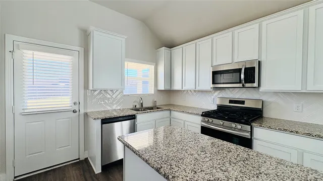 a kitchen with granite countertop a sink stove and cabinets