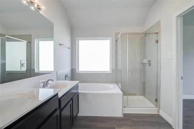 a bathroom with a tub sink shower and two mirror