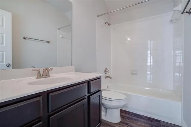 a bathroom with a granite countertop sink toilet a mirror and bathtub