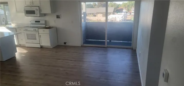 an empty room with wooden floor cabinet and windows