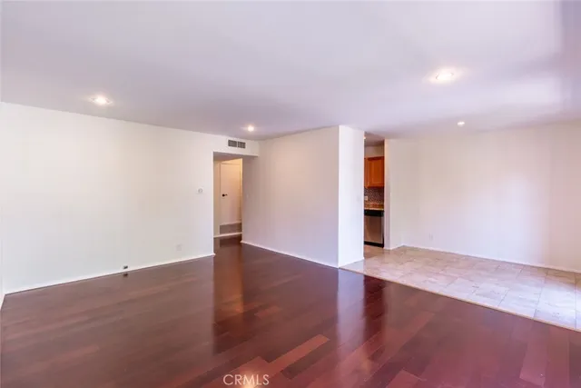 an empty room with wooden floor and natural light