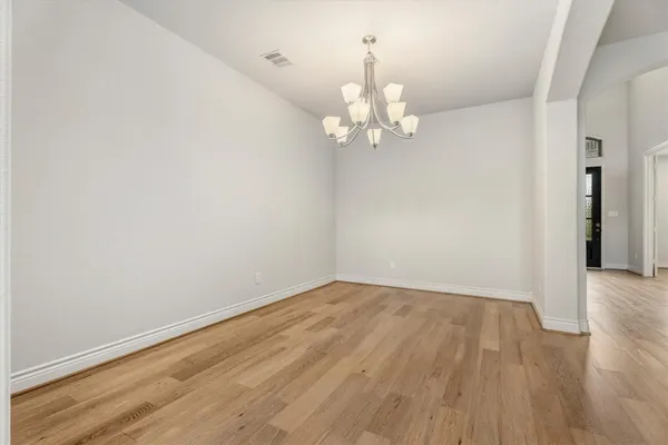 an empty room with wooden floor and chandelier