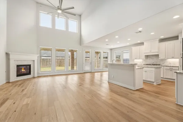 a view of an empty room with kitchen and a window